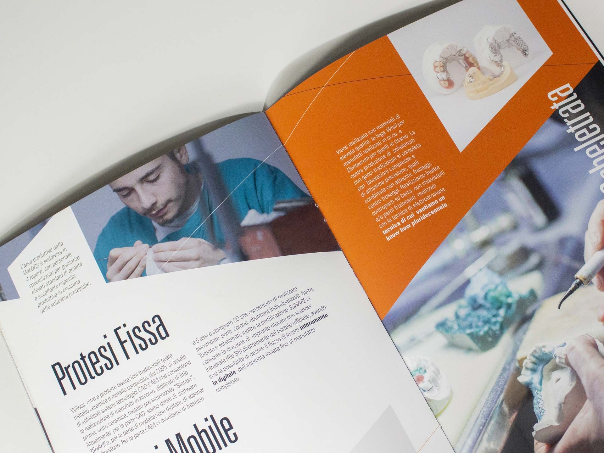 Una brochure per clinica dentale aperta con layout arancione e bianco audace, titoli di sezione 'Protesi Fissa' e 'Mobile', testo multicolonna e foto professionali di un tecnico dentale al lavoro. La progettazione grafica professionale per brochure mediche, cataloghi clinici e pubblicazioni sanitarie garantisce una comunicazione chiara e credibile con pazienti e partner.