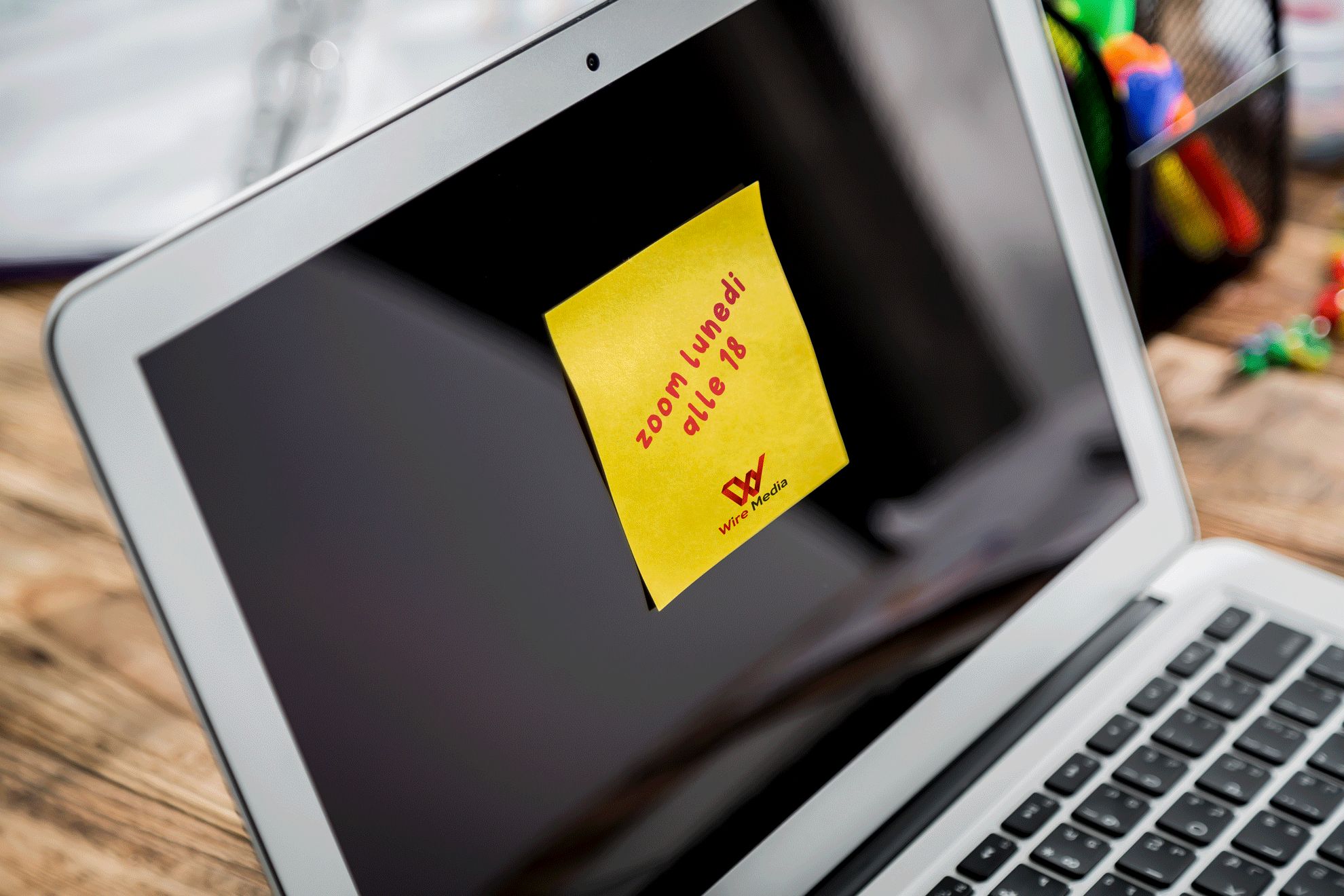 Un post-it giallo brandizzato con logo rosso e testo promemoria manoscritto incollato sullo schermo MacBook su scrivania in legno. Questi blocchi post-it personalizzati (25, 50 o 100 fogli in 6 formati standard) trasformano i foglietti adesivi quotidiani in potenti strumenti di brand — ideali come gadget ufficio, omaggi clienti e strumenti di brand awareness che mantengono il logo visibile ogni g…