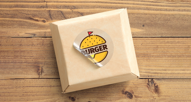 Adesivo trasparente rotondo logo burger colorato su scatola cartone kraft per packaging alimentare. Sprint24.
