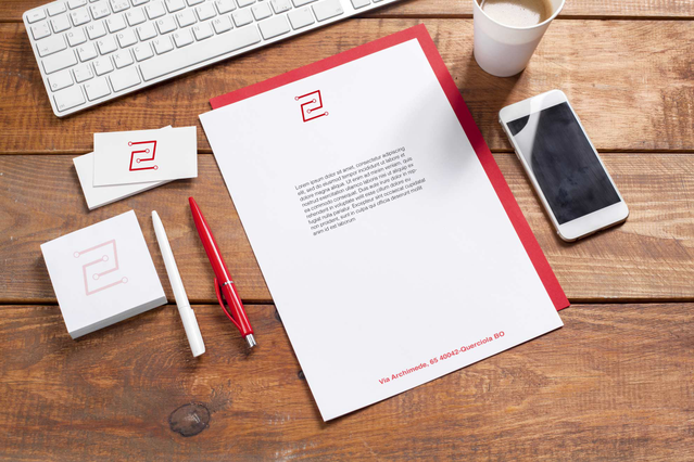 Carta intestata aziendale in piano su scrivania di legno Carta intestata brandizzata logo rosso su scrivania con biglietti, penna e caffe. Cancelleria Sprint24.