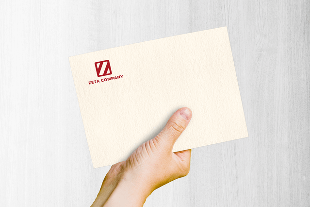 Mano con busta Vellum White crema con logo rosso. Texture morbida elegante per corrispondenza brand premium.