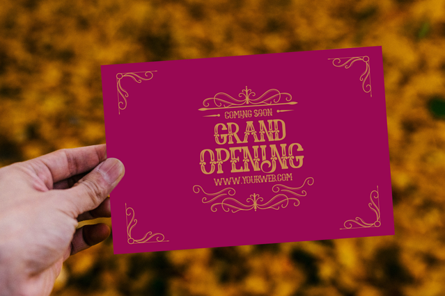 Mano con cartolina magenta Grand Opening tipografia ornata dorata. 400gr stampa premium Sprint24.