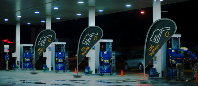 Installazione professionale di bandiera a goccia presso una stazione di servizio con branding carburante illuminato. Questa segnaletica esterna garantisce alta visibilità per la pubblicità di benzinai in ogni momento della giornata. Le bandiere a goccia personalizzabili sono ideali per la promozione di distributori di carburante.